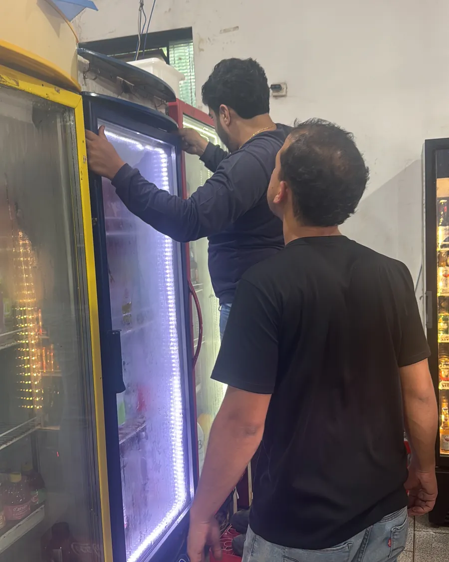 Técnico da RF Refrigeração revisando uma expositora em um comércio