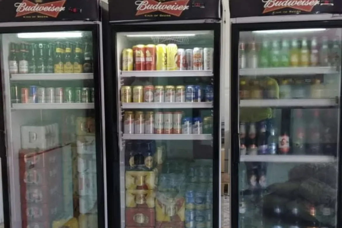 Três expositoras de bebidas cheias em um comércio